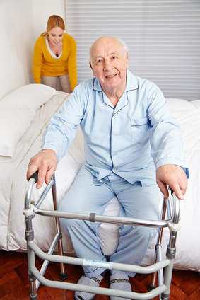 Senior am Bett zu Hause mit Gehhilfe